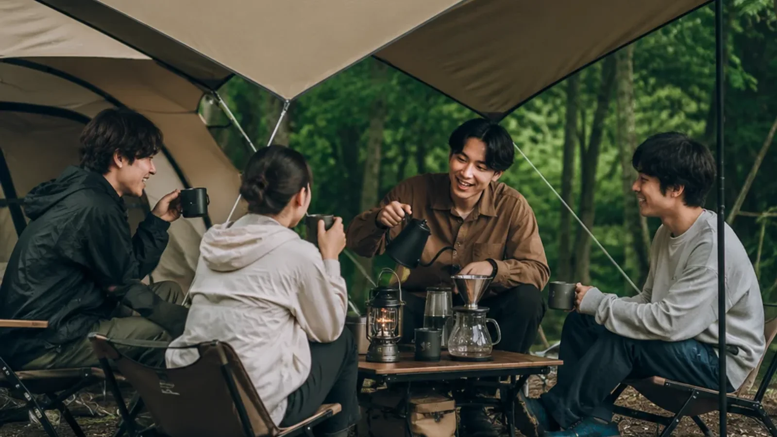 タープの下で友人四人がコーヒーを楽しむ様子