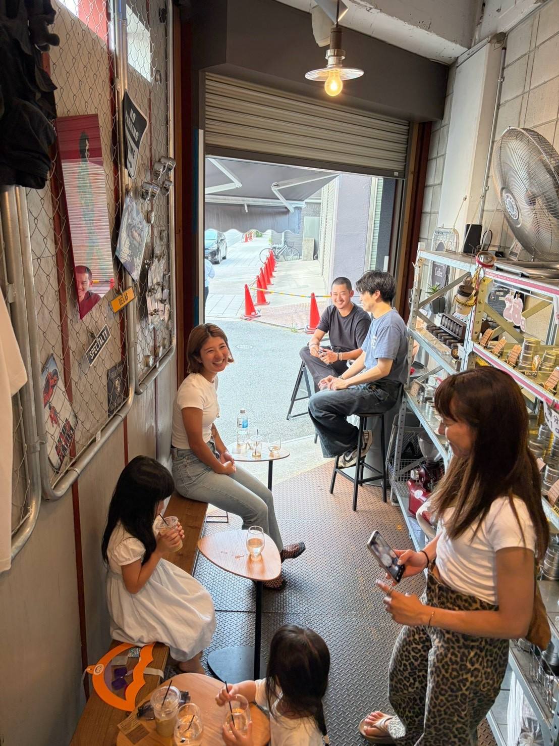 開け放したシャッターの店内でコーヒーを楽しむお客さま