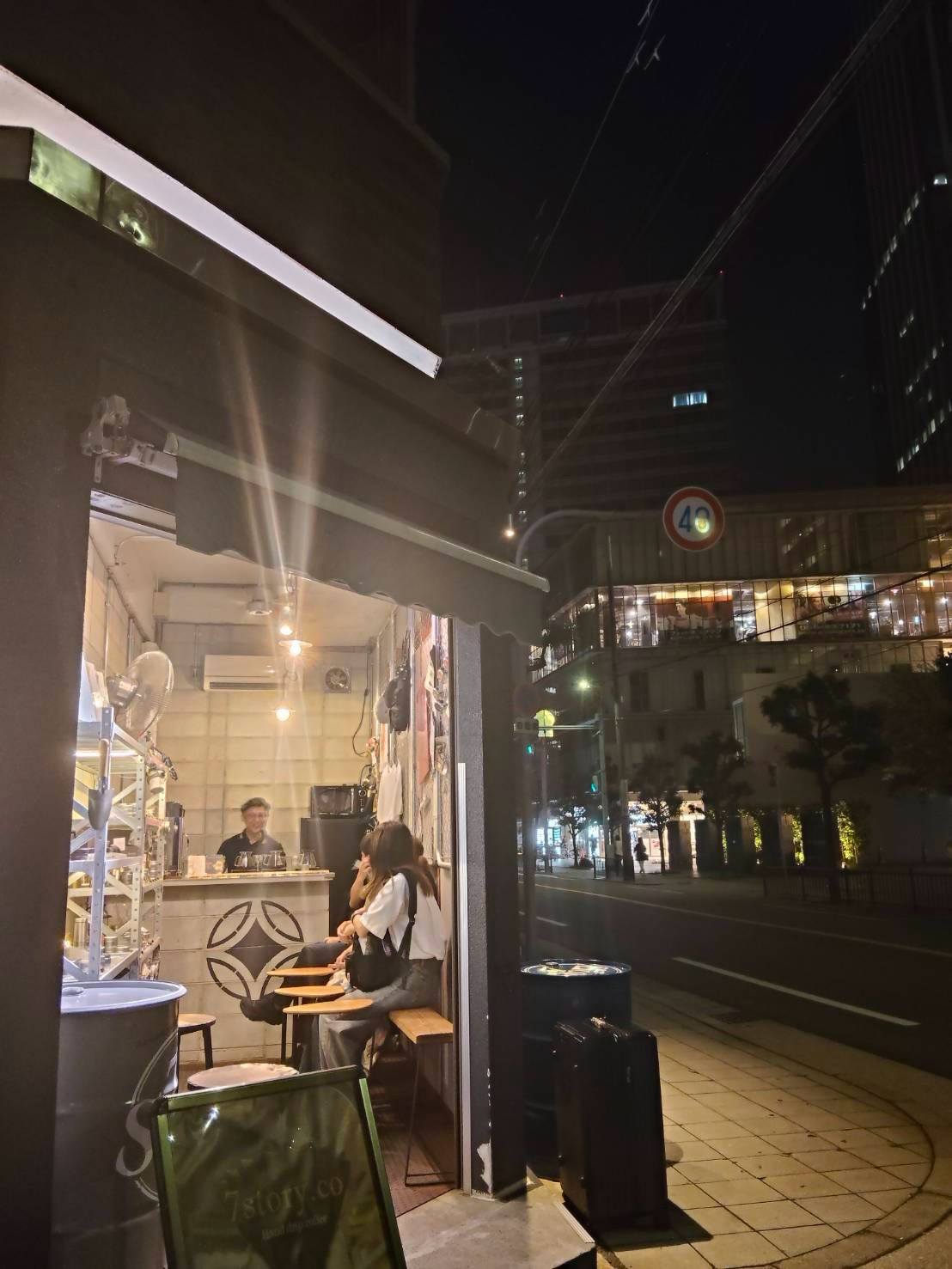 夜の街角で明かりが灯る7story.coの店先