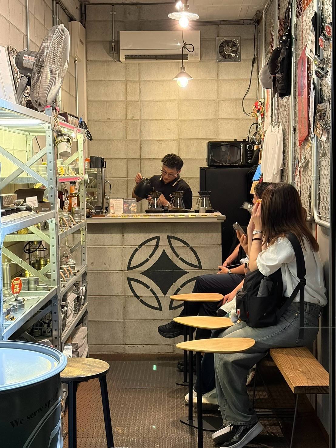 カウンターでハンドドリップするバリスタと店内のお客さま